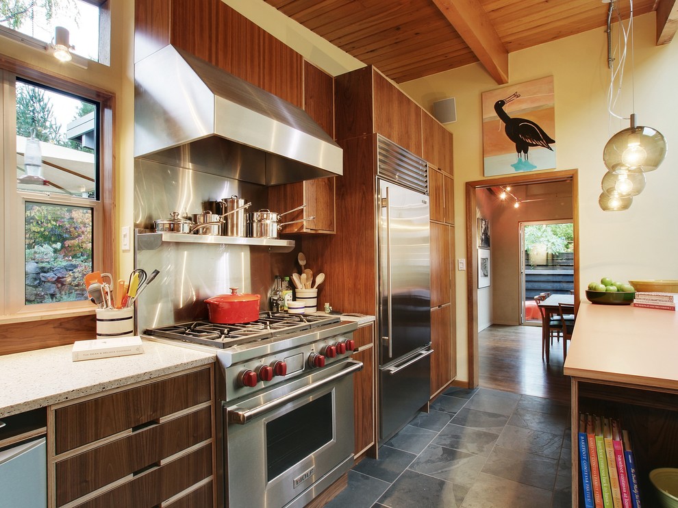 Exempel på ett mellanstort modernt kök, med släta luckor, rostfria vitvaror, stänkskydd med metallisk yta, stänkskydd i metallkakel, skiffergolv, skåp i mörkt trä, granitbänkskiva och svart golv