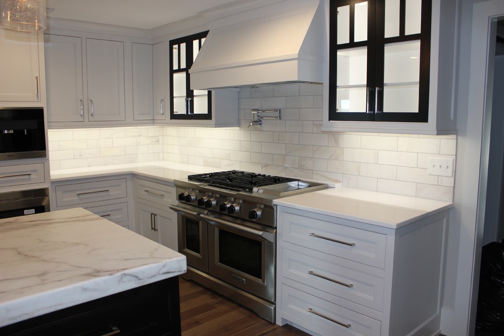 Example of a huge transitional medium tone wood floor eat-in kitchen design in Other with a farmhouse sink, shaker cabinets, white cabinets, marble countertops, white backsplash, marble backsplash, stainless steel appliances and an island