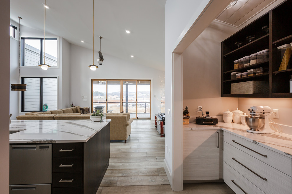 Foto på ett mellanstort funkis vit kök, med en undermonterad diskho, släta luckor, grå skåp, marmorbänkskiva, vitt stänkskydd, stänkskydd i marmor, rostfria vitvaror, ljust trägolv, en köksö och brunt golv