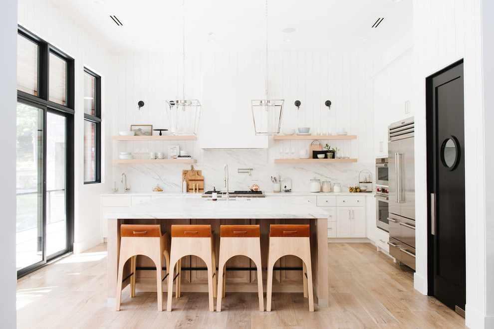 Idéer för stora lantliga vitt l-kök, med vita skåp, marmorbänkskiva, flerfärgad stänkskydd, stänkskydd i marmor, rostfria vitvaror, ljust trägolv och en köksö