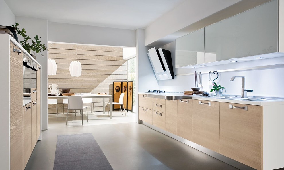 Inspiration for a medium sized modern galley enclosed kitchen in Miami with flat-panel cabinets, light wood cabinets, white splashback, stainless steel appliances and grey floors.