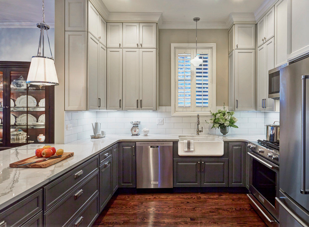 Example of a mid-sized farmhouse u-shaped dark wood floor open concept kitchen design in Other with a farmhouse sink, recessed-panel cabinets, gray cabinets, quartz countertops, white backsplash, subway tile backsplash, stainless steel appliances and a peninsula