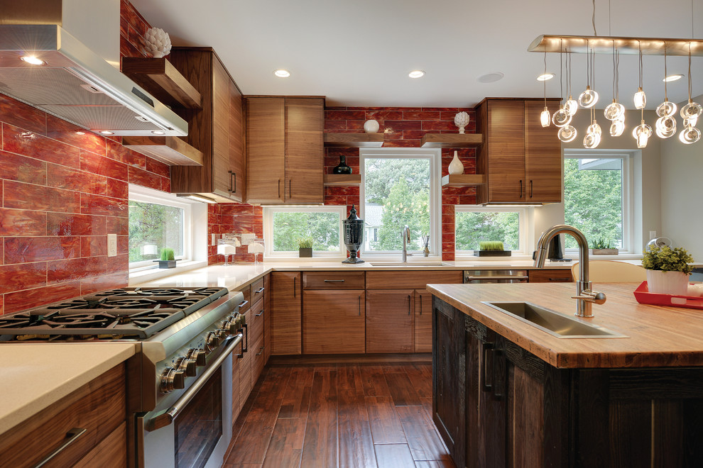 Exempel på ett modernt l-kök, med en enkel diskho, skåp i mellenmörkt trä, rött stänkskydd, rostfria vitvaror, mellanmörkt trägolv och en köksö