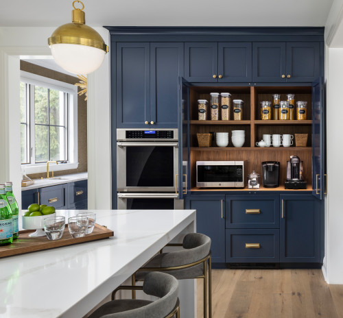 Premium RTA cabinets Canada: navy shaker kitchen cabinets with brass handles, pantry/coffee bar with exposed wood shelves, double wall oven, white quartz waterfall island.