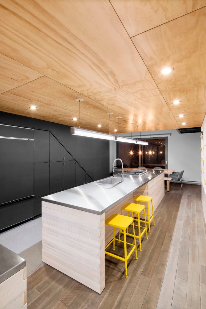 Mid-sized trendy galley medium tone wood floor and multicolored floor eat-in kitchen photo in Montreal with a single-bowl sink, flat-panel cabinets, white cabinets, stainless steel countertops, white backsplash, stainless steel appliances, two islands and gray countertops