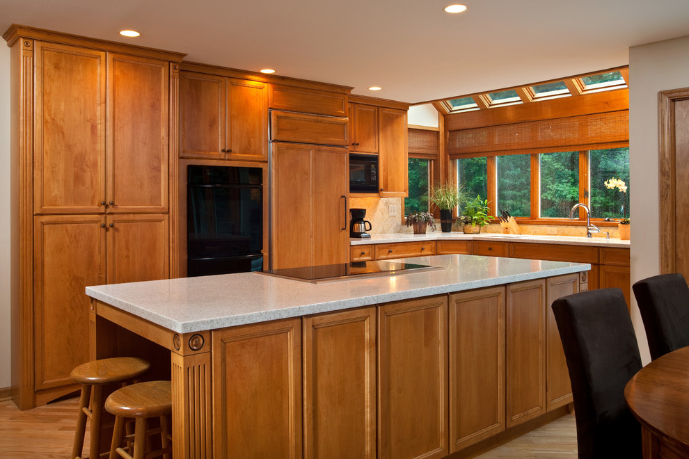 Foto di una cucina classica di medie dimensioni con lavello sottopiano, ante con riquadro incassato, ante in legno scuro, top in marmo, elettrodomestici neri e parquet chiaro