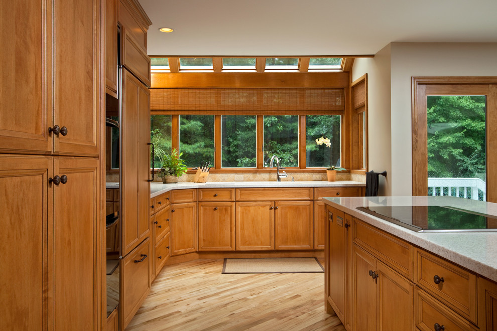 Example of a classic l-shaped kitchen design in Boston with recessed-panel cabinets, medium tone wood cabinets, beige backsplash and paneled appliances