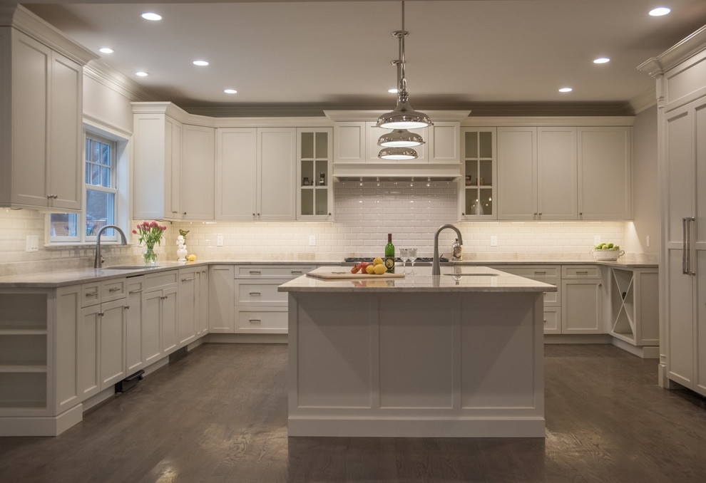 Modern inredning av ett mellanstort kök, med en undermonterad diskho, skåp i shakerstil, vita skåp, granitbänkskiva, vitt stänkskydd, stänkskydd i keramik, integrerade vitvaror, mellanmörkt trägolv, en köksö och brunt golv