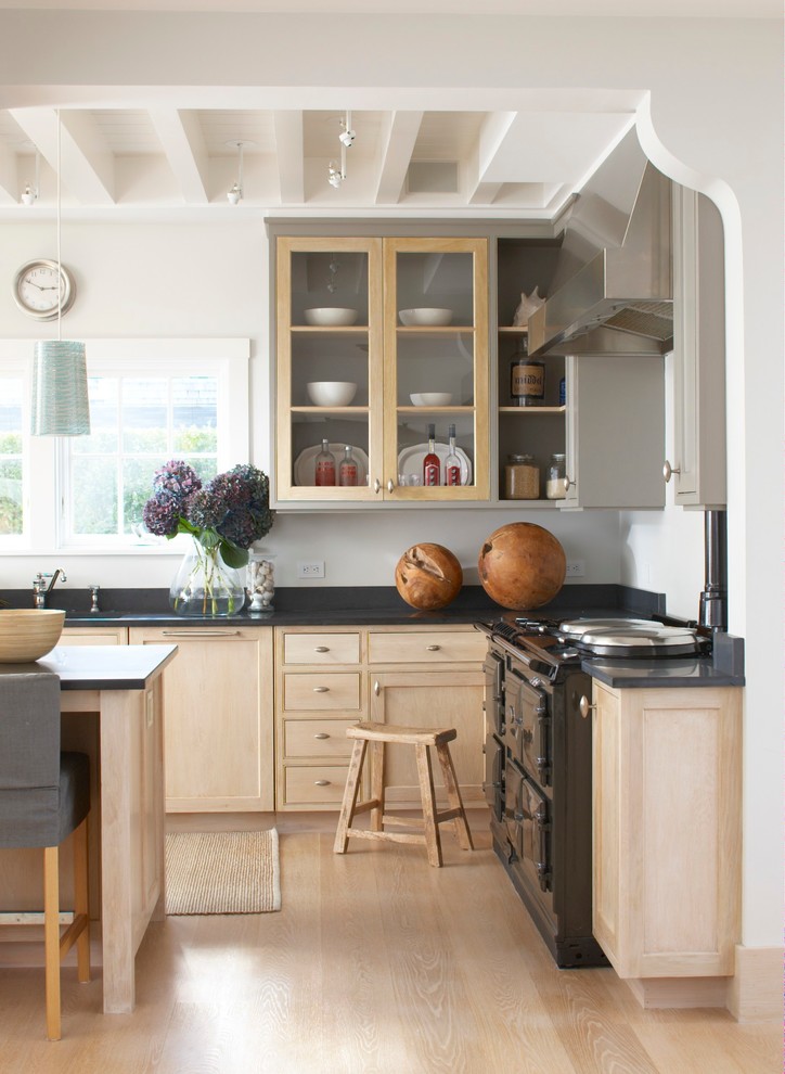 Aménagement d'une cuisine classique en L et bois clair avec un placard à porte shaker, un électroménager noir, parquet clair et îlot.