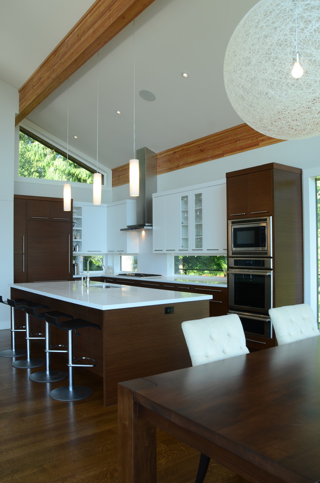 Große Moderne Wohnküche in L-Form mit Unterbauwaschbecken, flächenbündigen Schrankfronten, weißen Schränken, Quarzwerkstein-Arbeitsplatte, Küchengeräten aus Edelstahl, dunklem Holzboden und Kücheninsel in Vancouver