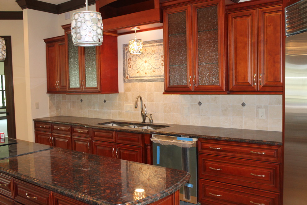 Foto di una grande cucina tradizionale con lavello sottopiano, ante di vetro, ante rosse, top in granito, paraspruzzi beige, paraspruzzi con piastrelle in pietra e elettrodomestici in acciaio inossidabile