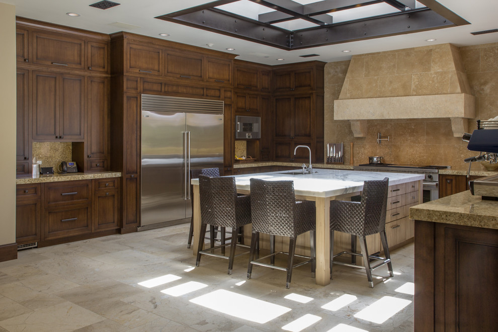 Example of a mountain style u-shaped eat-in kitchen design in San Diego with an undermount sink, recessed-panel cabinets, medium tone wood cabinets, limestone countertops, beige backsplash, stone tile backsplash and stainless steel appliances