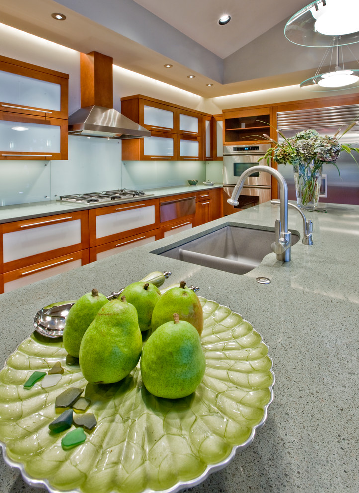Foto på ett stort funkis kök, med en undermonterad diskho, luckor med glaspanel, skåp i mellenmörkt trä, granitbänkskiva, grönt stänkskydd, glaspanel som stänkskydd, rostfria vitvaror, mellanmörkt trägolv och en köksö