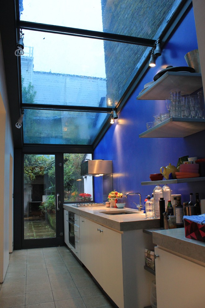 Example of a mid-sized minimalist galley limestone floor eat-in kitchen design in London with a single-bowl sink, flat-panel cabinets, limestone countertops, blue backsplash and stainless steel appliances