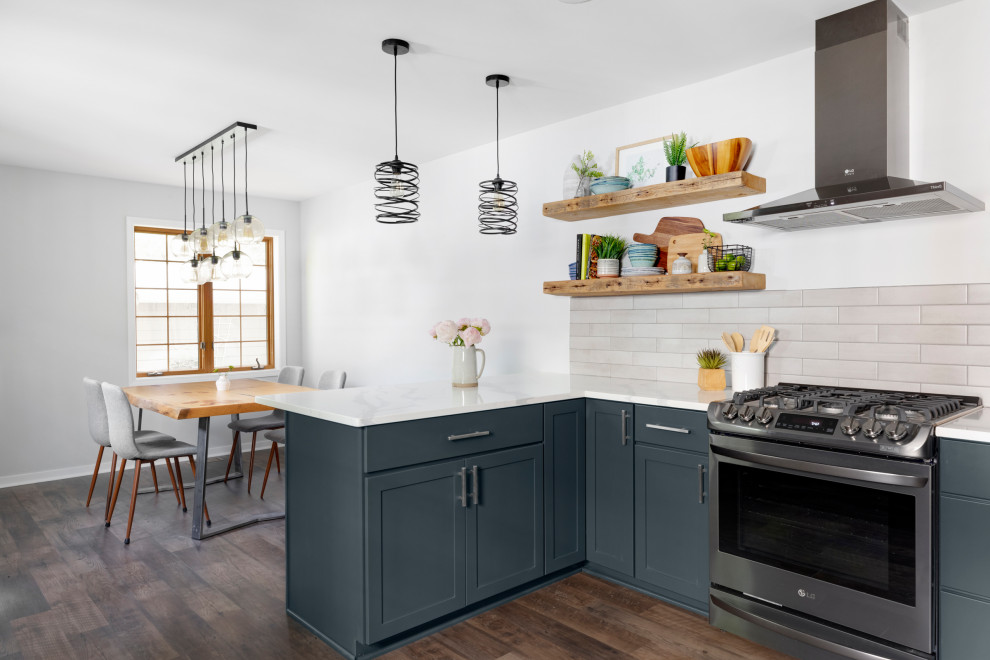 Klassisk inredning av ett mellanstort vit vitt kök, med en undermonterad diskho, skåp i shakerstil, blå skåp, bänkskiva i kvarts, grått stänkskydd, stänkskydd i keramik, rostfria vitvaror, vinylgolv, en halv köksö och brunt golv