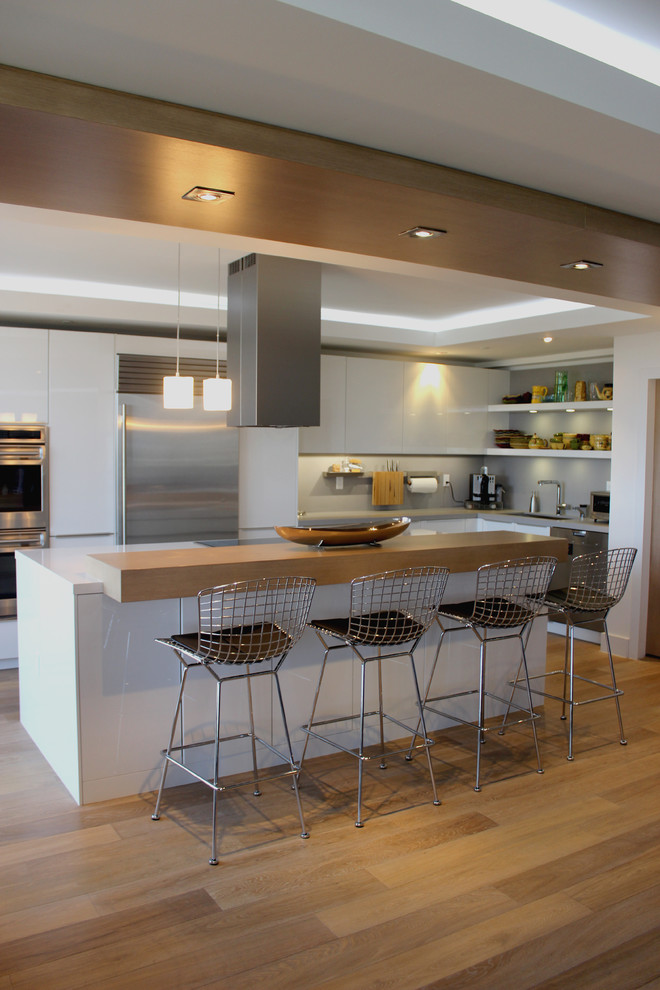 Eat-in kitchen - mid-sized modern l-shaped medium tone wood floor eat-in kitchen idea in Miami with an undermount sink, flat-panel cabinets, white cabinets, quartz countertops, gray backsplash, stone slab backsplash, stainless steel appliances and an island