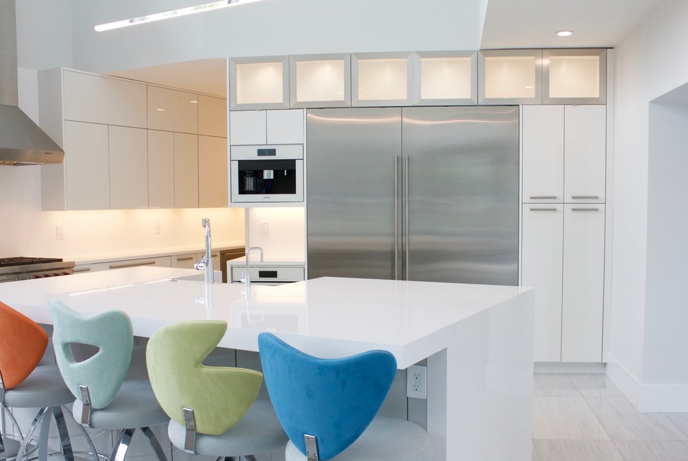 Photo of a large contemporary u-shaped open plan kitchen in Miami with a belfast sink, flat-panel cabinets, white cabinets, engineered stone countertops, white splashback, stainless steel appliances, marble flooring and an island.
