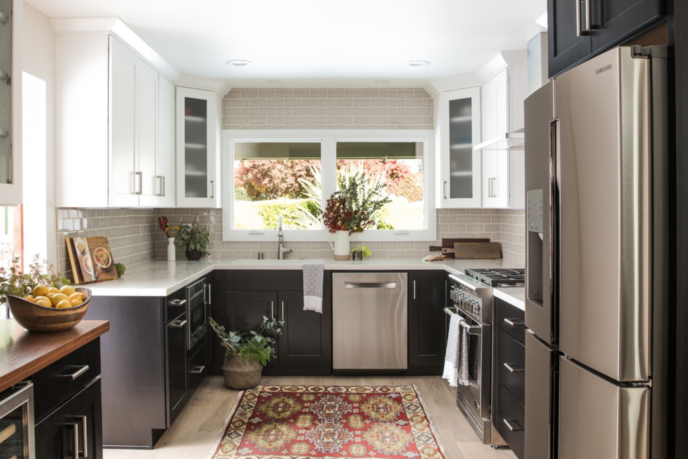 Medium sized classic galley enclosed kitchen in San Francisco with a built-in sink, shaker cabinets, black cabinets, engineered stone countertops, grey splashback, ceramic splashback, stainless steel appliances, light hardwood flooring, no island and white floors.