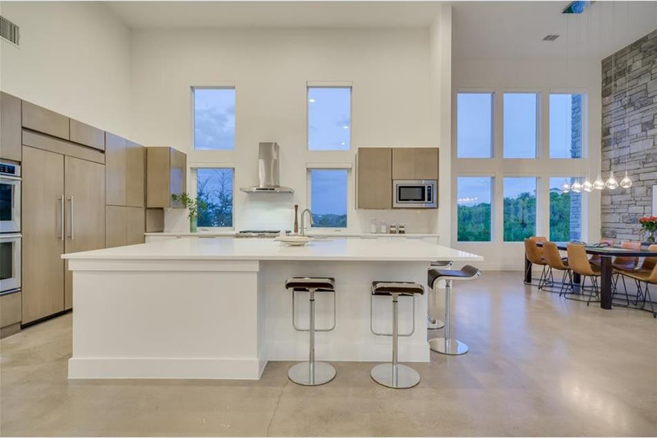 Idéer för att renovera ett mellanstort funkis vit vitt kök, med en undermonterad diskho, släta luckor, skåp i mellenmörkt trä, granitbänkskiva, vitt stänkskydd, stänkskydd i porslinskakel, rostfria vitvaror, betonggolv, en köksö och flerfärgat golv