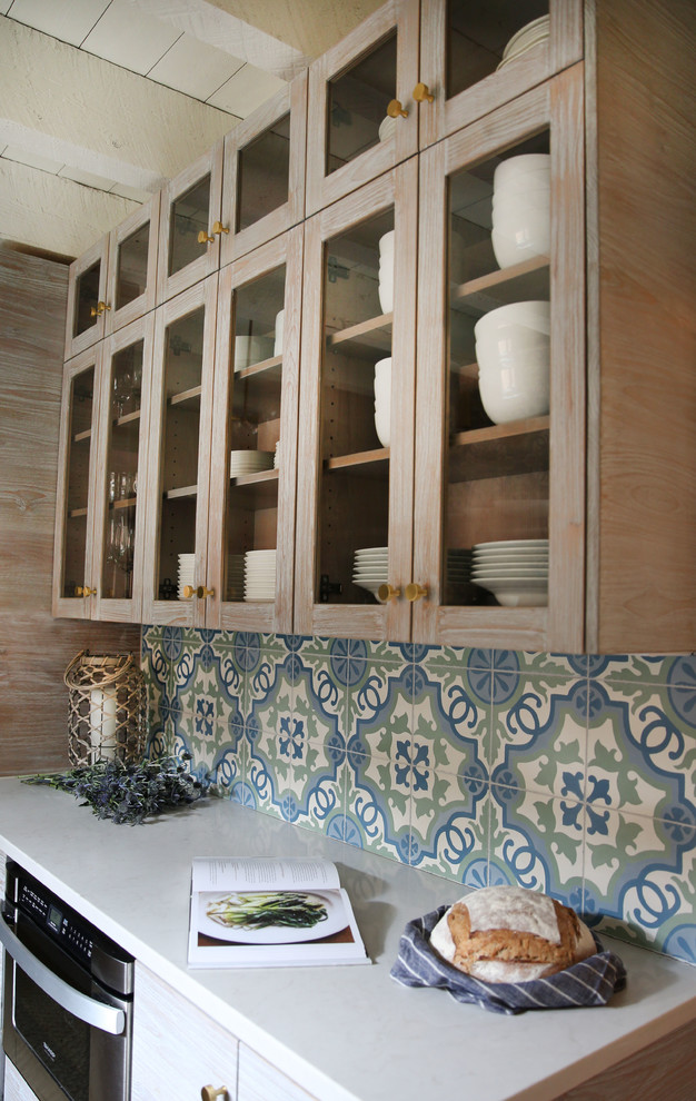 Immagine di una cucina minimalista con lavello sottopiano, ante lisce, ante bianche, top in quarzite, paraspruzzi blu, paraspruzzi con piastrelle di cemento, elettrodomestici in acciaio inossidabile e pavimento in mattoni