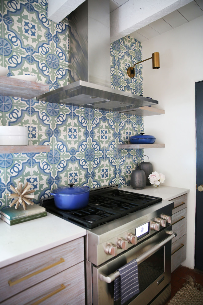 Immagine di una cucina moderna con lavello sottopiano, ante bianche, top in quarzite, paraspruzzi blu, paraspruzzi con piastrelle di cemento, elettrodomestici in acciaio inossidabile e pavimento in mattoni