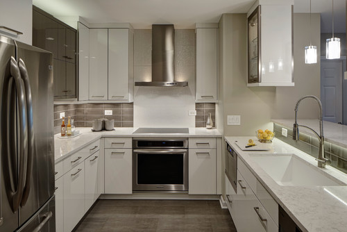 Modern U-shaped kitchen with white cabinets and gray artificial stone countertops featuring stainless steel appliances