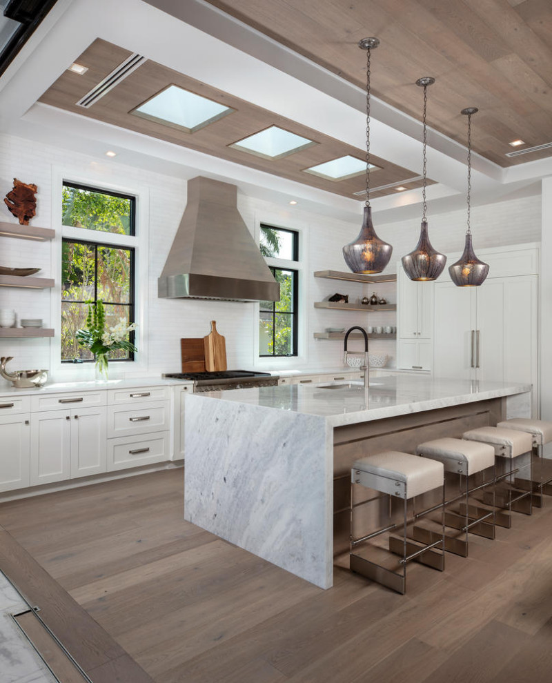 Inspiration for a contemporary u-shaped kitchen in Miami with a submerged sink, shaker cabinets, white cabinets, white splashback, stainless steel appliances, medium hardwood flooring, an island, brown floors, white worktops and a drop ceiling.