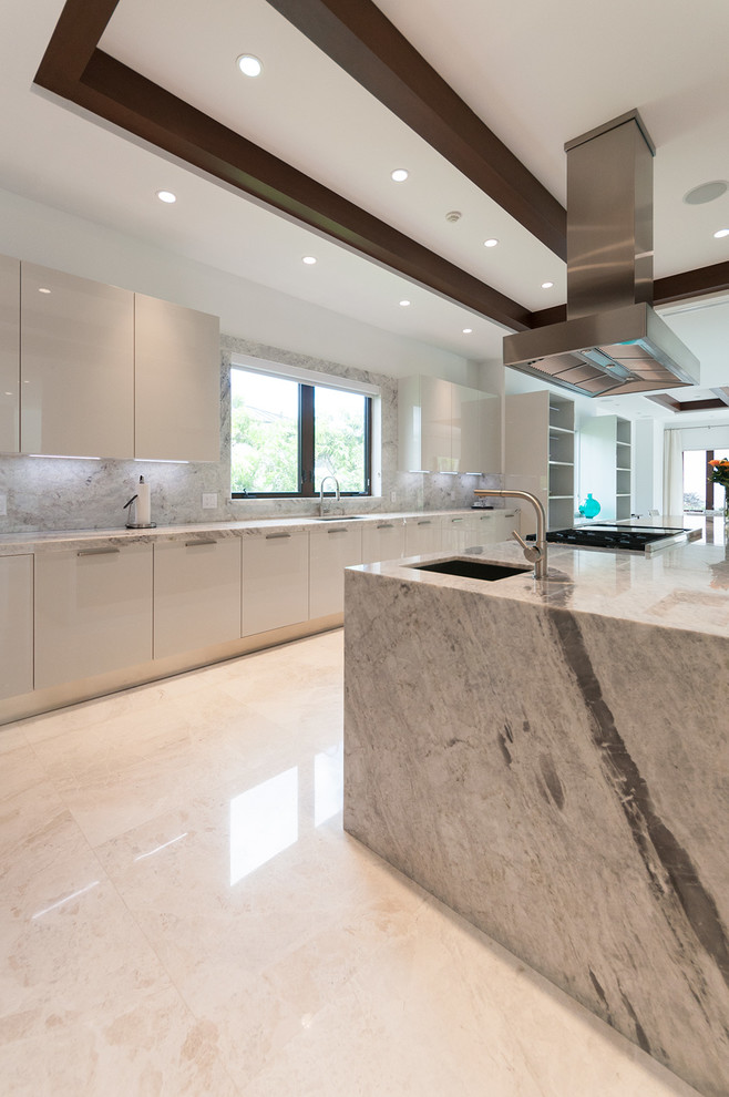 Contemporary u-shaped kitchen in Miami with a built-in sink, flat-panel cabinets, white cabinets, grey splashback, stone tiled splashback and stainless steel appliances.