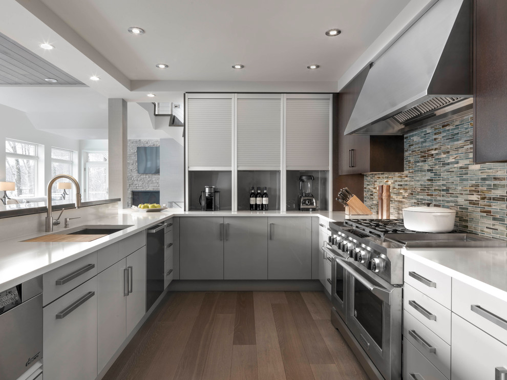 Inspiration for a large contemporary l-shaped open plan kitchen in Burlington with a submerged sink, flat-panel cabinets, dark wood cabinets, composite countertops, multi-coloured splashback, mosaic tiled splashback, stainless steel appliances, light hardwood flooring, a breakfast bar and beige floors.