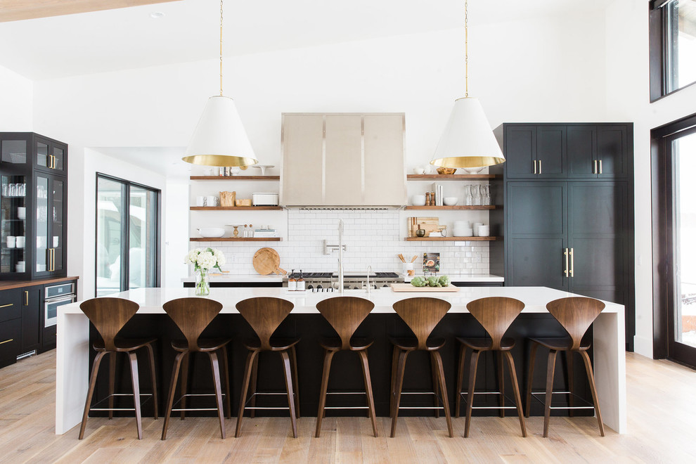 ソルトレイクシティにあるトランジショナルスタイルのおしゃれなアイランドキッチン (白いキッチンパネル、サブウェイタイルのキッチンパネル、淡色無垢フローリング、オープンシェルフ、パネルと同色の調理設備、グレーとクリーム色) の写真