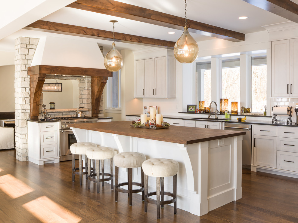 Example of a large cottage chic u-shaped dark wood floor eat-in kitchen design in Minneapolis with an undermount sink, shaker cabinets, white cabinets, wood countertops, white backsplash, subway tile backsplash, stainless steel appliances and an island