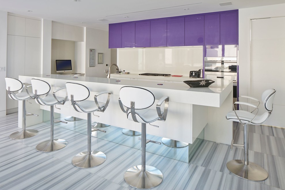 Cette photo montre une cuisine parallèle tendance avec un placard à porte plane, des portes de placard violettes, une crédence blanche, une crédence en feuille de verre, un électroménager blanc, îlot, un sol gris et un plan de travail blanc.