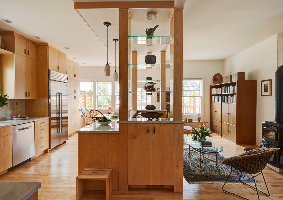 Exempel på ett stort modernt kök, med en enkel diskho, släta luckor, skåp i ljust trä, bänkskiva i glas, grått stänkskydd, stänkskydd i glaskakel, rostfria vitvaror, ljust trägolv, en köksö och beiget golv