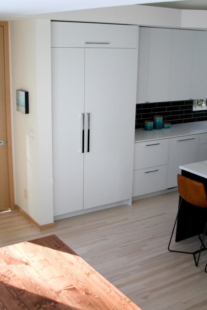 Diseño de cocinas en L minimalista grande con una isla, armarios con paneles lisos, puertas de armario blancas, electrodomésticos con paneles y suelo de madera clara