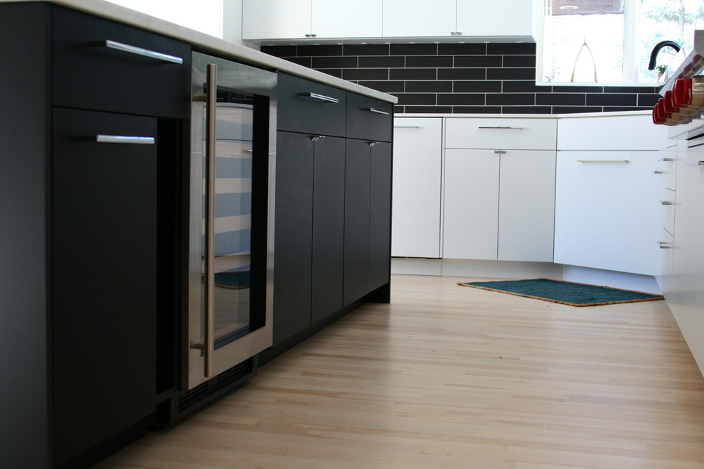 Modelo de cocinas en L minimalista grande con una isla, armarios con paneles lisos, salpicadero negro, electrodomésticos de acero inoxidable y suelo de madera clara