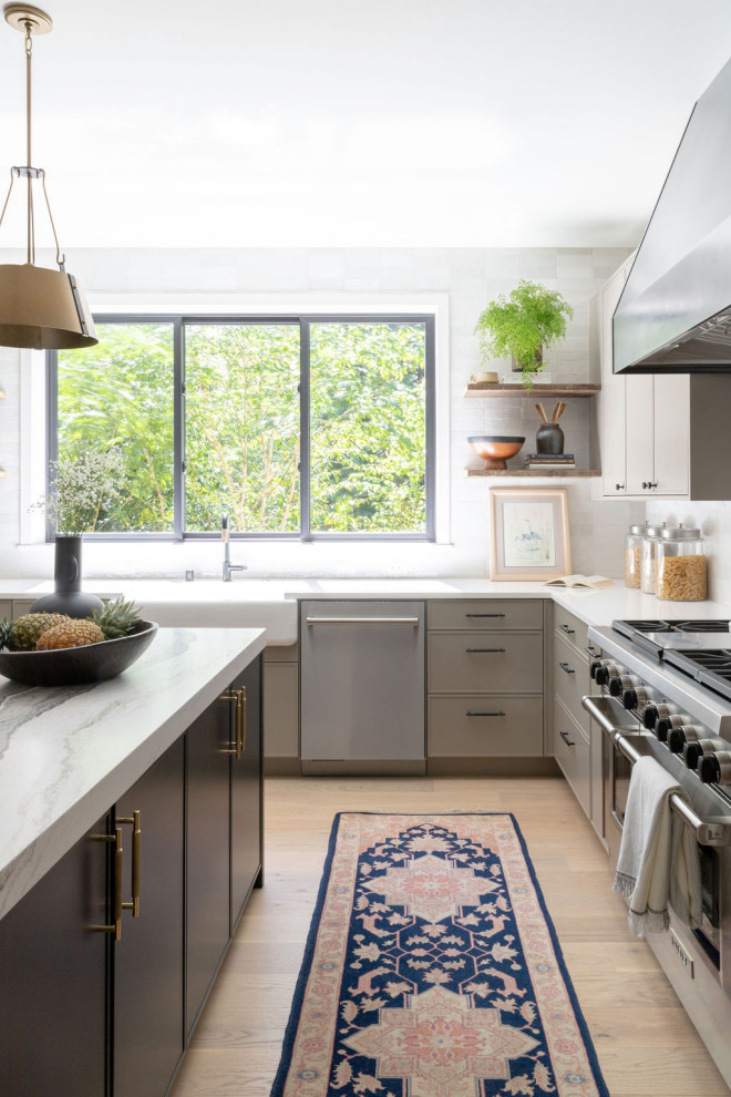 Moderne Küche in L-Form mit Landhausspüle, flächenbündigen Schrankfronten, grauen Schränken, Küchengeräten aus Edelstahl, braunem Holzboden, Kücheninsel, braunem Boden und weißer Arbeitsplatte in Seattle