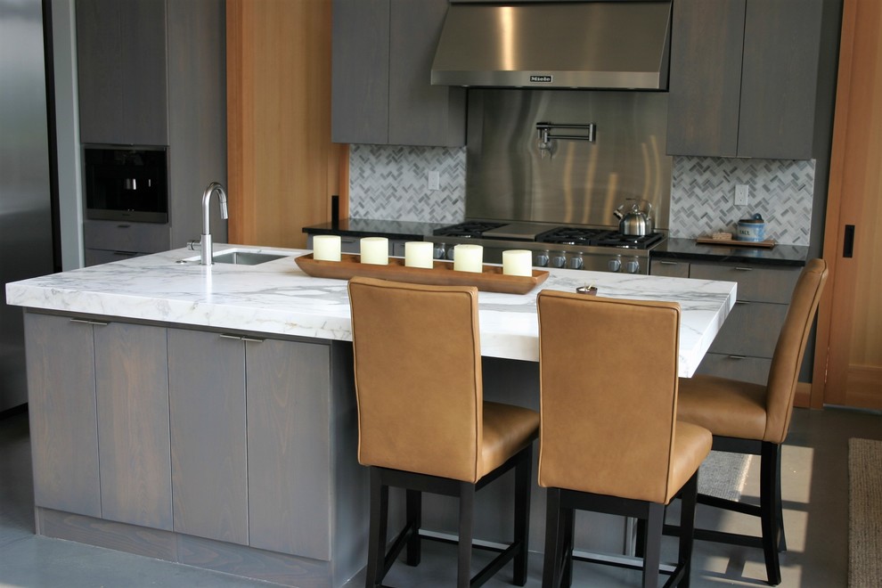 Foto di una cucina minimalista di medie dimensioni con lavello sottopiano, ante lisce, ante grigie, top in marmo, paraspruzzi grigio, paraspruzzi con piastrelle di metallo, pavimento in cemento, pavimento grigio e top bianco