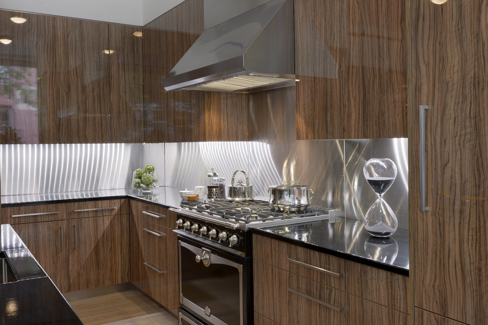 Immagine di una grande cucina design con lavello sottopiano, ante lisce, ante in legno scuro, paraspruzzi a effetto metallico, elettrodomestici in acciaio inossidabile e parquet chiaro
