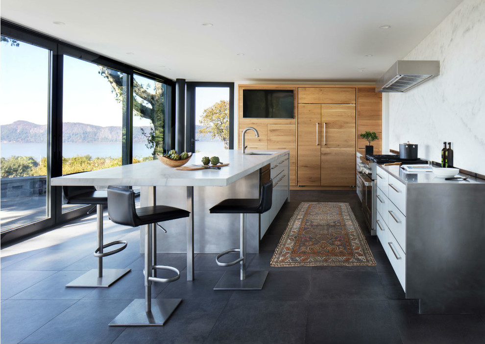 Eat-in kitchen - large contemporary l-shaped porcelain tile eat-in kitchen idea in New York with flat-panel cabinets, light wood cabinets, marble countertops, white backsplash, marble backsplash, paneled appliances, an island and white countertops