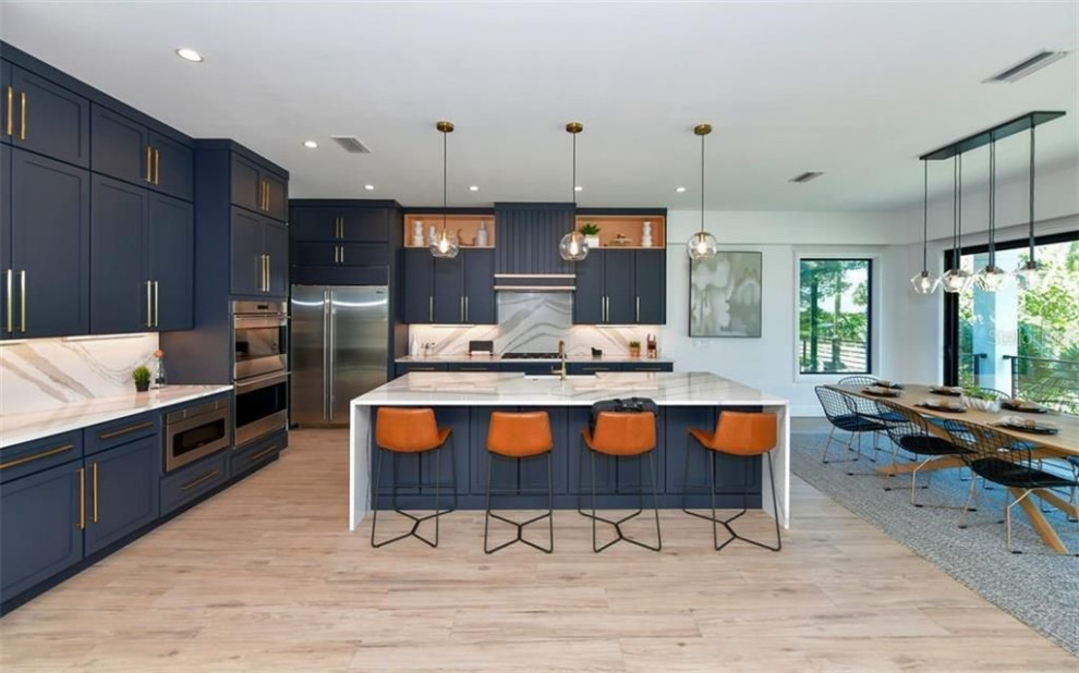 Inredning av ett modernt stort flerfärgad flerfärgat kök och matrum, med blå skåp, marmorbänkskiva, flerfärgad stänkskydd, stänkskydd i marmor, rostfria vitvaror, ljust trägolv och en köksö