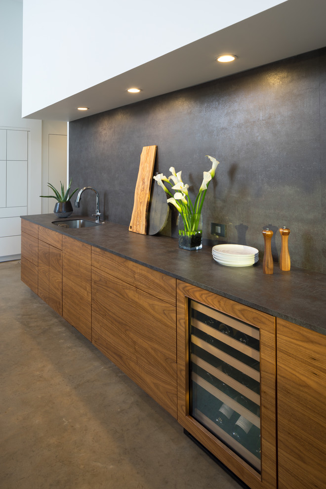 Esempio di una cucina moderna di medie dimensioni con lavello sottopiano, ante lisce, top in quarzo composito, paraspruzzi nero, elettrodomestici bianchi e pavimento in cemento