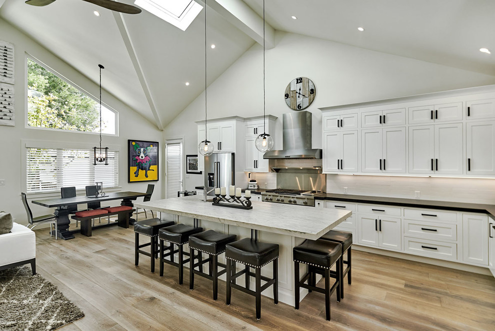Inspiration for a large modern l-shaped dark wood floor and beige floor open concept kitchen remodel in San Francisco with an undermount sink, beaded inset cabinets, white cabinets, granite countertops, white backsplash, ceramic backsplash, stainless steel appliances and an island