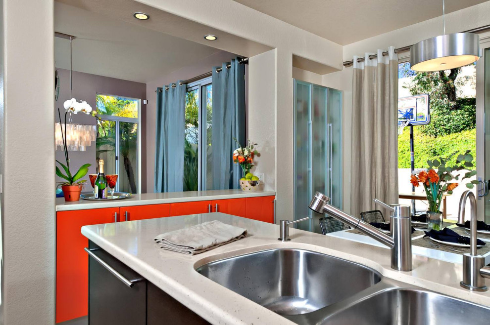 Photo of a small modern l-shaped kitchen/diner in San Diego with a double-bowl sink, flat-panel cabinets, orange cabinets, engineered stone countertops, beige splashback, ceramic splashback, stainless steel appliances, porcelain flooring, beige floors, beige worktops and a coffered ceiling.