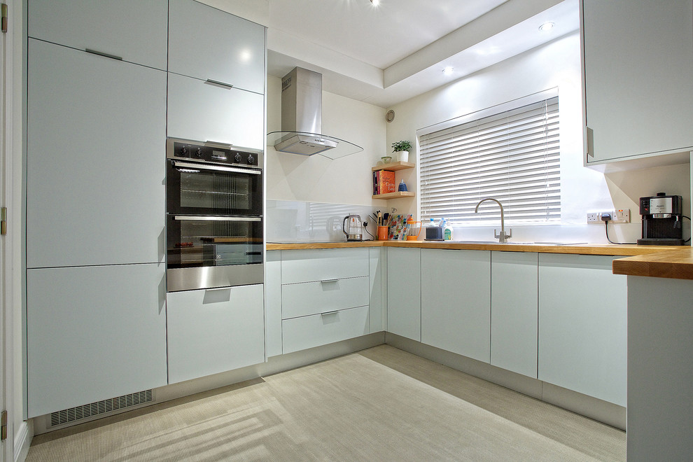 Esempio di una cucina design di medie dimensioni con ante lisce, ante blu, top in legno, paraspruzzi con lastra di vetro e elettrodomestici da incasso