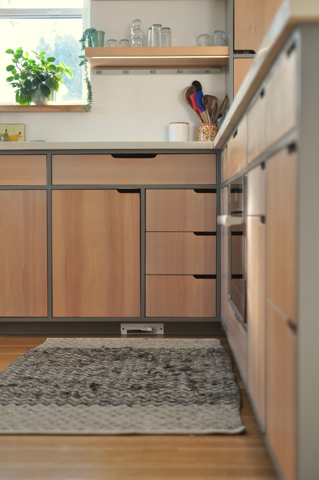 Esempio di una cucina minimalista di medie dimensioni con ante lisce e ante in legno chiaro