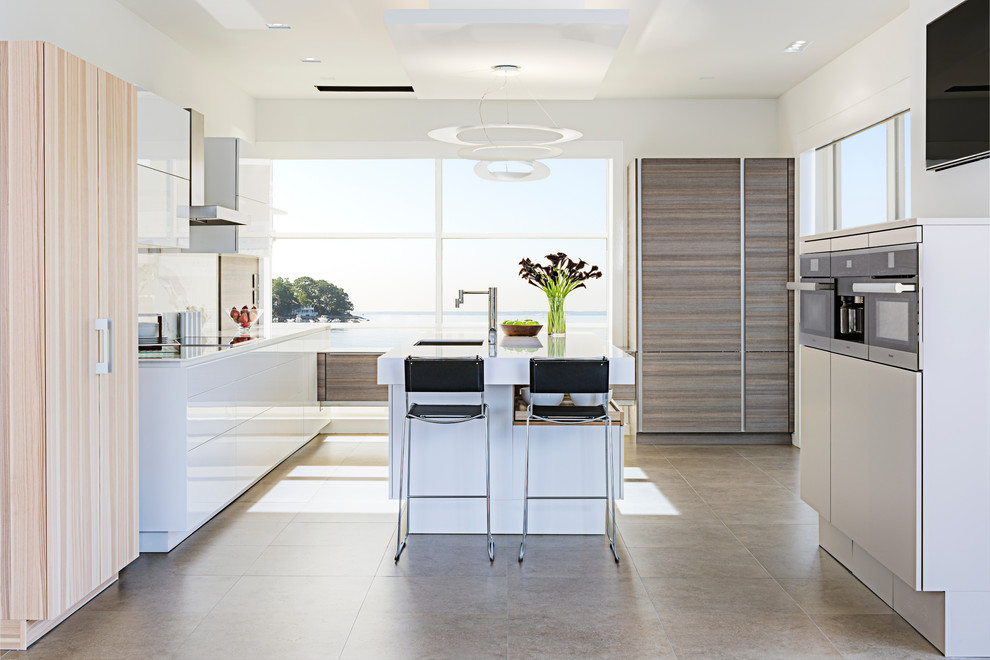Design ideas for a large contemporary l-shaped open plan kitchen in New York with a submerged sink, flat-panel cabinets, white cabinets, engineered stone countertops, white splashback, stone slab splashback, integrated appliances, porcelain flooring and an island.