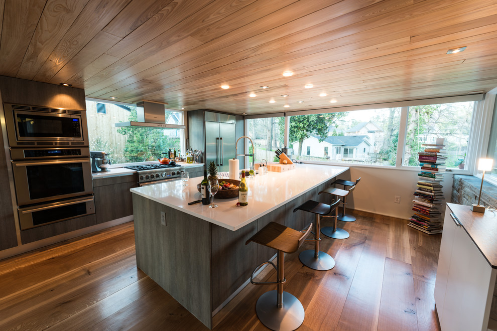 Aménagement d'une grande cuisine américaine parallèle moderne en bois vieilli avec un placard à porte plane, un plan de travail en quartz, un électroménager en acier inoxydable, un sol en bois brun et îlot.