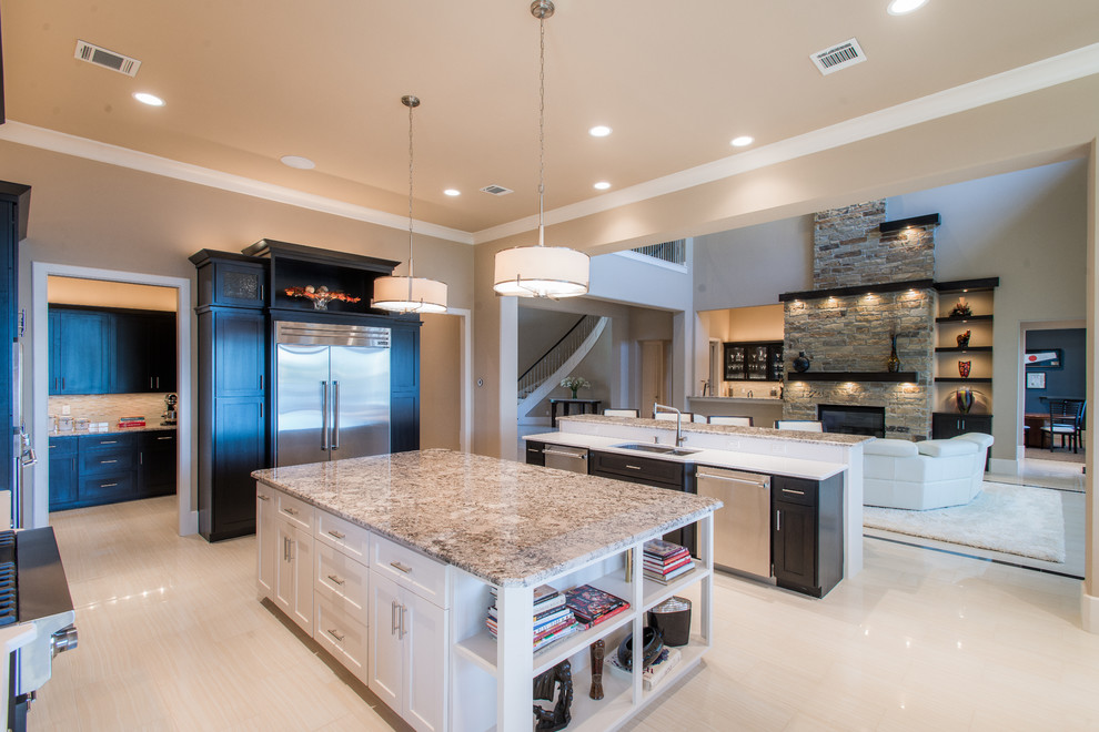 Example of a large minimalist u-shaped porcelain tile open concept kitchen design in Houston with a farmhouse sink, beaded inset cabinets, dark wood cabinets, granite countertops, beige backsplash, stone tile backsplash, stainless steel appliances and two islands