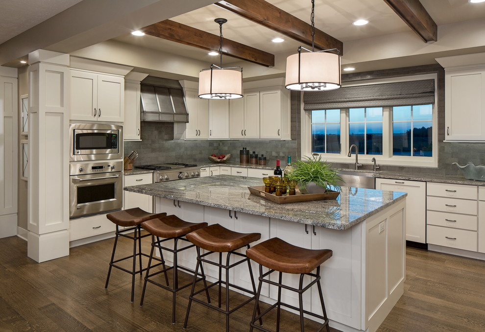 Klassische Küche in grau-weiß in L-Form mit Landhausspüle, Schrankfronten im Shaker-Stil, weißen Schränken, Küchenrückwand in Grau, Küchengeräten aus Edelstahl, dunklem Holzboden und Kücheninsel in Omaha
