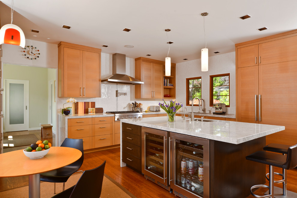 Modern inredning av ett kök och matrum, med släta luckor, integrerade vitvaror, skåp i mellenmörkt trä och vitt stänkskydd